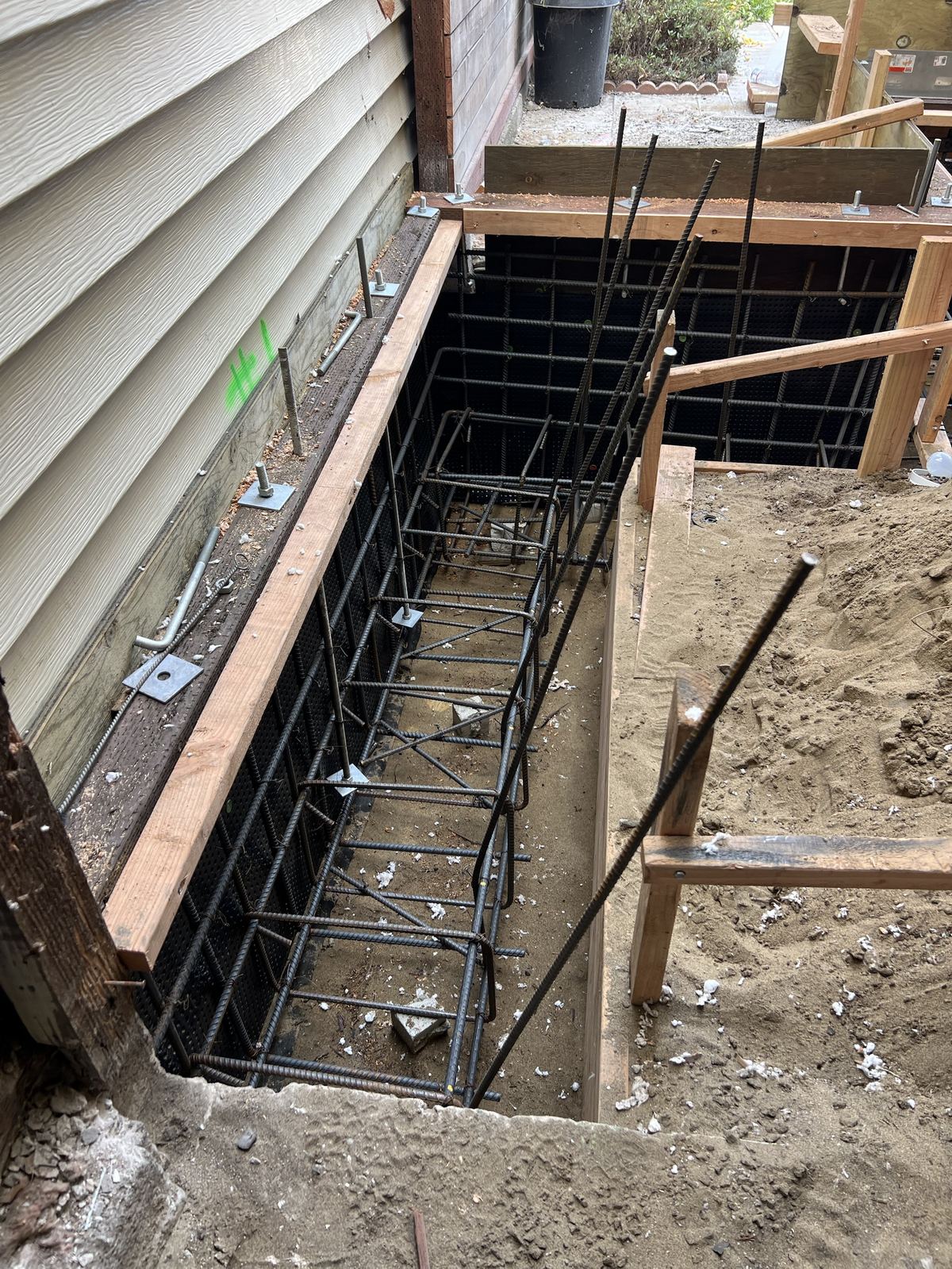 Rebar cage tied and set in footing trench along house foundation